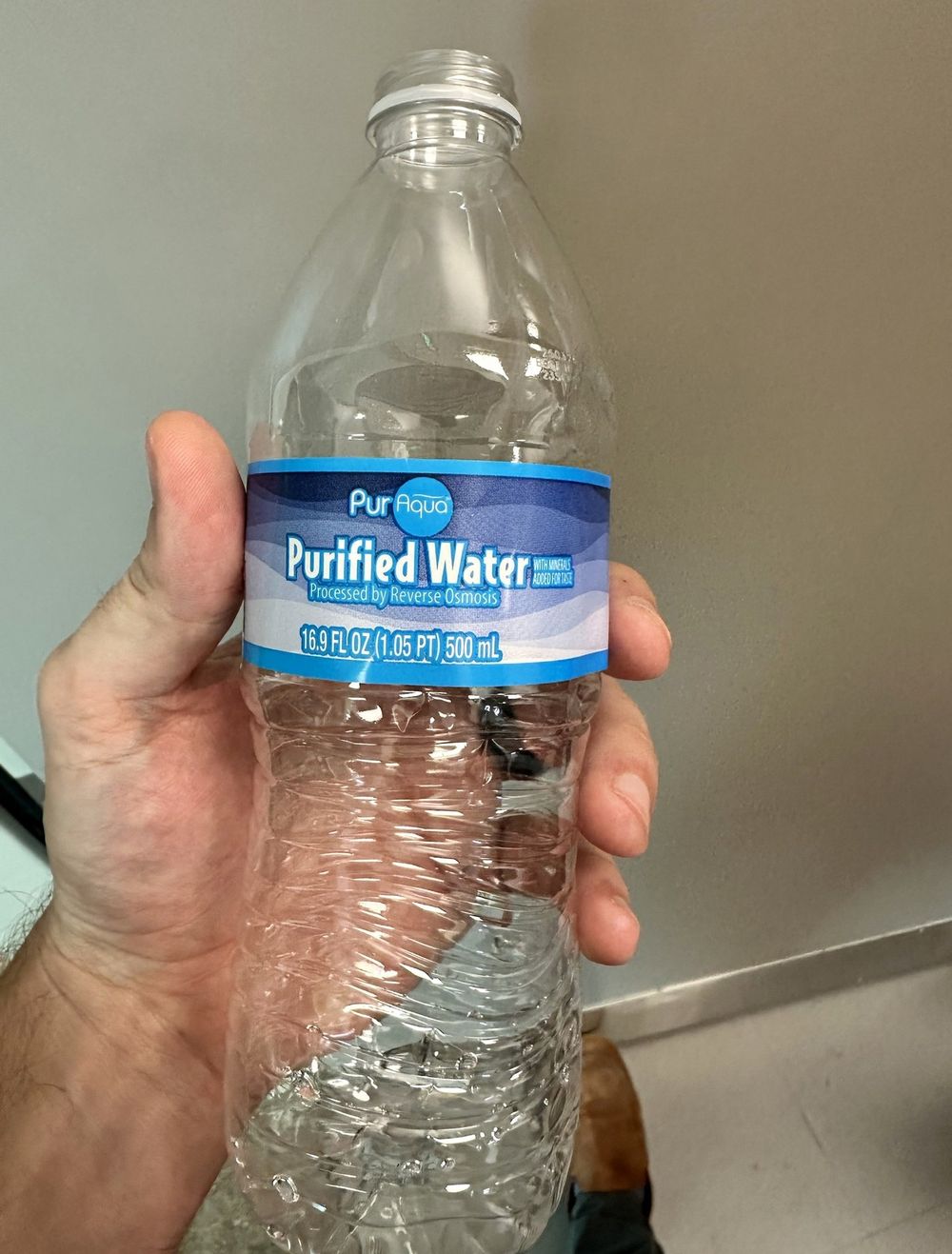 A hand holding a store-bought 500 mL water bottle, the same bottle later broken down in the lab